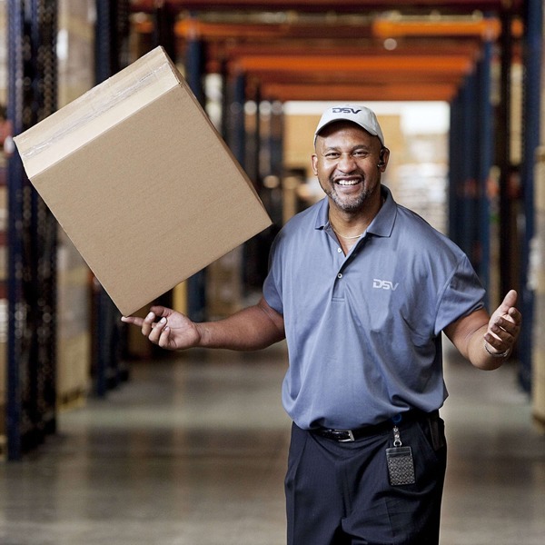 Smiling man in DSV clothing balancing brown box on his index finger